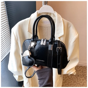 Close-up of black shell-shaped handbag featuring silver hardware and heart charm