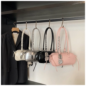 Detail of four stylish baguette bags in silver, white, black and pink with metal charms