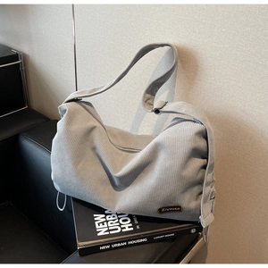 Detailed texture of grey corduroy hobo bag with adjustable strap and leather brand label