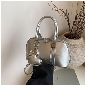 Detailed close-up of a silver metallic shell bag with a large padded heart-shaped charm