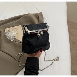 Close-up of black retro leather bag with silver kiss-lock and delicate chain strap
