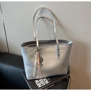Detail of silver tote bag with pleated metallic texture and tennis racket pendant charm