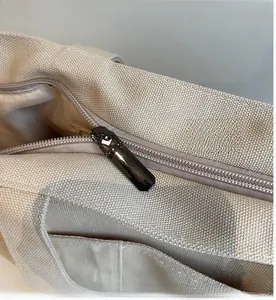Detail of smooth metal zipper on large capacity beige canvas tote bag for women