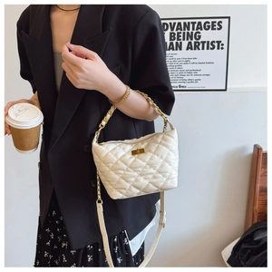 Détail d'un sac à main blanc matelassé avec fermoir tournant doré et chaîne