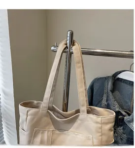 Detail of a minimalist cream canvas tote bag showing strong double handles and outer pocket