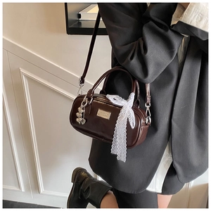 Detailed view of deep brown leather bowling bag with silver heart charm and lace ribbon