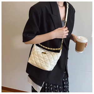 Détail du sac matelassé blanc avec fermoir doré et bandoulière chaîne porté par un mannequin