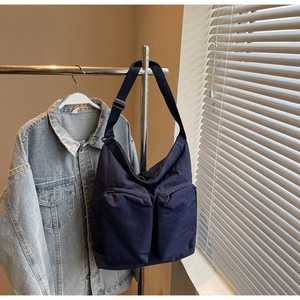 Detail of navy blue canvas crossbody bag with multiple functional zipper pockets