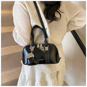 Close-up of black glossy shell handbag with heart charm and silver hardware accents