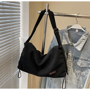 Detail of black corduroy hobo bag showing thick ribbed texture and leather logo patch