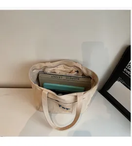 Top view of large cream canvas tote bag interior showing spacious storage and blue embroidery