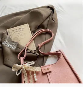 Detail of light pink PU leather bucket bag with pearl and lace floral charm accessory