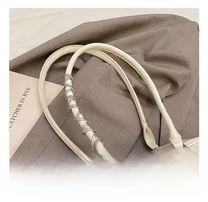 Detail of cream leather shoulder bag featuring a silver spiral metallic handle decoration