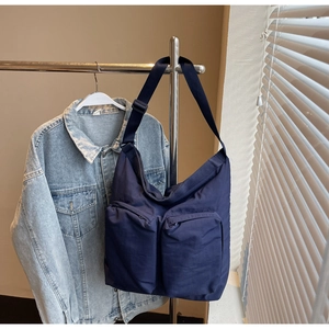Detail of navy blue nylon messenger bag with double front zip pockets and wide strap