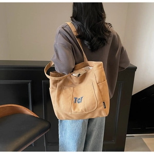Detail view of large canvas tote bag with TCT embroidery and side pocket on model