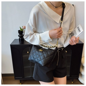 Détail du cuir matelassé noir et de la bandoulière en chaîne dorée du sac à bandoulière
