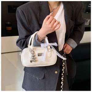 Detail of cream bowling bag with white lace bow and silver heart charm decoration
