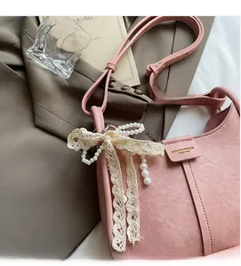 Pink matte leather bucket bag featuring pearl charms and delicate lace bow details