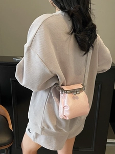 Pink glossy leather crossbody phone bag with silver chain strap shown on a model