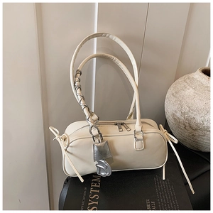 Detail of cream rectangular handbag with silver chain handles and bow decorations
