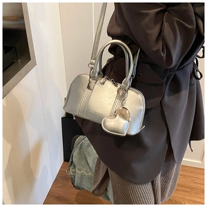 Close-up of metallic silver shell bag with heart charm and textured details