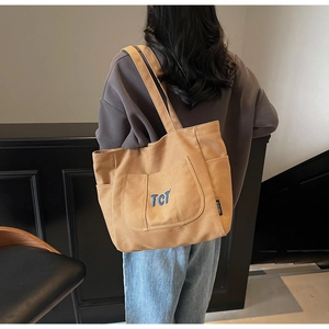 Detail of camel canvas tote bag with blue TCT embroidery and multiple utility pockets