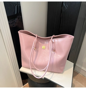 Close-up of bright pink tote bag showing glossy texture and golden metal logo plate