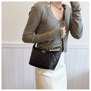 Détail du sac à bandoulière en cuir noir matelassé avec chaîne dorée et fermoir en métal