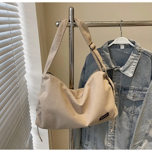 Close-up of beige corduroy tote bag showing thick ribbed texture and brand label detail