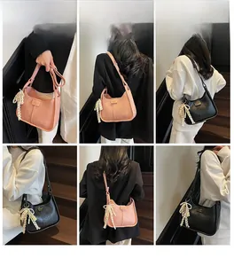 Detailed view of fashionable semi-circular shoulder bag with pearl bow pendant and lace