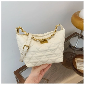 Détails du sac matelassé beige avec chaîne dorée et fermoir rotatif métallique