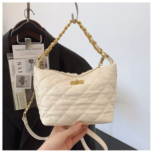 Détail d'un sac bandoulière matelassé crème avec chaîne dorée et fermoir pivotant en métal
