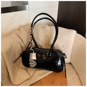 Detail of black glossy patent leather shoulder bag with silver metallic D pendant