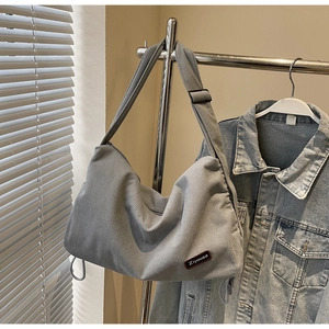 Detail of grey corduroy crossbody bag texture with adjustable strap and drawstring design