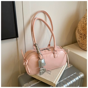 Detailed view of pink shoulder bag with bow knot and hanging metal letter charms