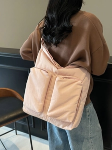 Pink large puffer tote bag with dual front zipper pockets shown on a shoulder model