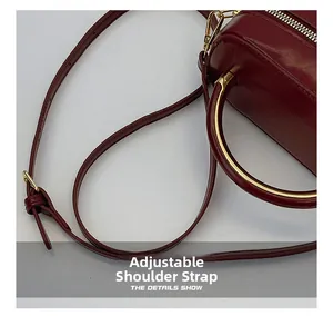 Detail of burgundy leather handbag showing adjustable strap and gold-tone hardware