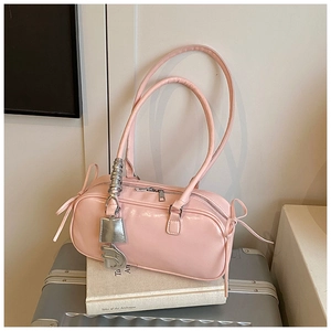 Detail view of pink leather baguette bag with silver hardware on a silver suitcase