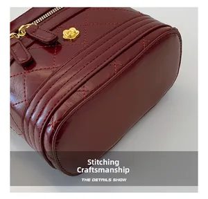 Detail of wine red quilted leather bag showing gold floral charm and reinforced stitching