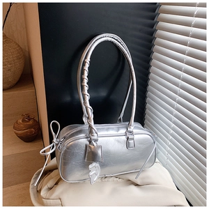 Detail view of silver wrinkled leather bag with metal D-charm and butterfly bow accents