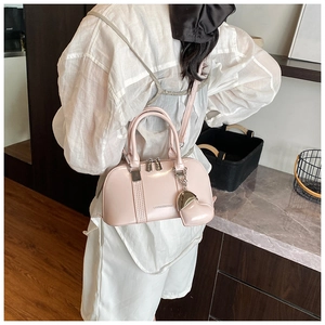 Detail view of pink shell bag with heart coin purse and adjustable crossbody strap