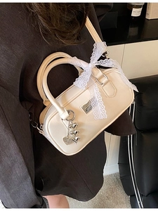Chic cream white bowling bag with lace bow and silver heart charms shown on model