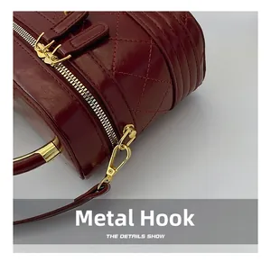 Detailed close-up of dark red quilted leather purse with premium gold metal hook and zipper