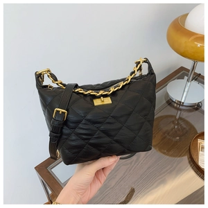 Détail du sac bandoulière en cuir noir matelassé avec chaîne dorée et fermoir tournant