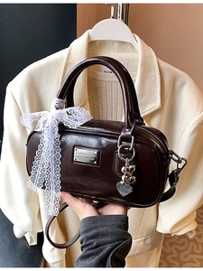 Chic dark brown glossy bowling bag with lace ribbon and heart charms for daily commute