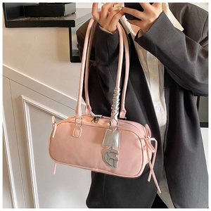 Detailed view of pink baguette bag with metallic charm and side bow accents