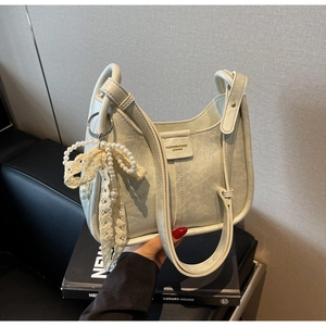 Detail of creamy white PU leather shoulder bag with decorative lace pearl bow charm