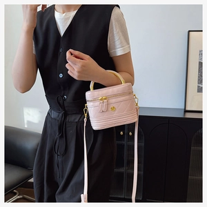 Close-up of pink quilted crossbody box bag featuring gold floral logo and metal handle