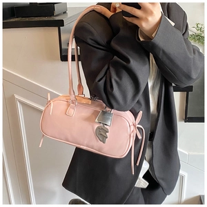 Pink baguette bag with silver padlock charm shown in a minimalist modern interior setting