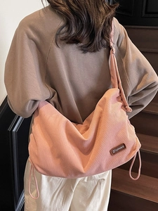 Pink corduroy crossbody bag with adjustable drawstrings and premium leather patch